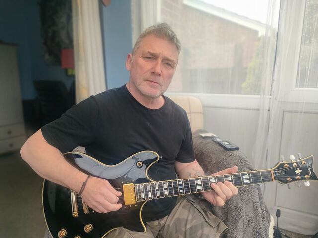 Carl playing a black electric guitar